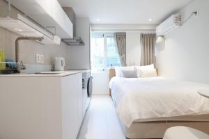 a small white bedroom with a bed and a sink at 더 신촌스테이 레지던스 in Seoul