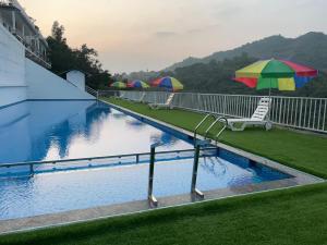 a swimming pool with chairs and umbrellas on a building at Mountain Breeze Neyyans in Attappādi