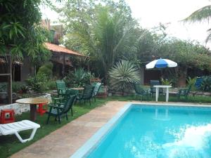 a swimming pool with chairs and a table and an umbrella at Pousada Chalé Suiço in Parnaíba