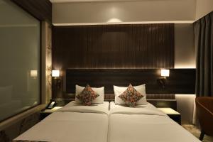 a bedroom with a large white bed with two pillows at Sio Suites in Navi Mumbai