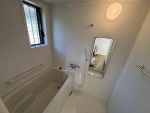 a white bathroom with a tub and a mirror at Exsaison SETOUCHI in Sakaide