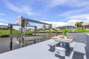 a patio with a table and benches on the water at Waterfront Oasis in Cape Coral