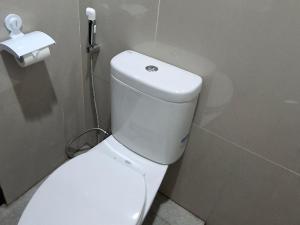a white toilet in a bathroom with a phone on the wall at Ndalem Livtuhayu in Godean +8 photos