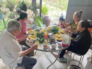 a group of people sitting around a table eating food at Vùng ven Homestay in Cho Lach