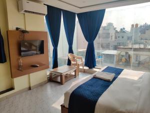 a bedroom with a bed and a large window at SB Royal Inn in Mysore
