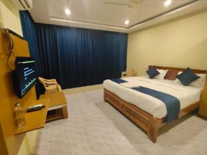 a bedroom with a bed and a television in it at SB Royal Inn in Mysore