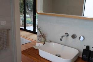 a bathroom with a white sink and a mirror at Driftwood Studio in Mount Martha +37 photos