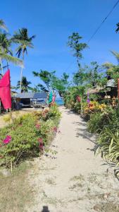 a dirt path leading to a beach with flowers at Bamboo Basecamp in El Nido +13 photos