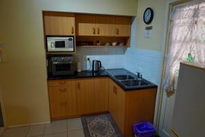 a small kitchen with a sink and a microwave at Curtis Cottage in Mount Tamborine +6 photos