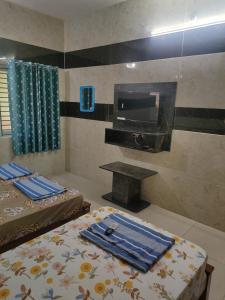 a hotel room with two beds and a television at HAnsHari Homestay in Kuttālam