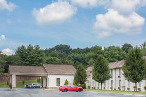 un grand bâtiment blanc avec une voiture rouge garée dans un parking dans l'établissement Super 8 by Wyndham Daleville/Roanoke, à Daleville