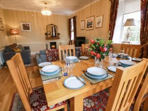 a dining room with a wooden table with plates and flowers at Clocktower - Culzean Castle in Maybole