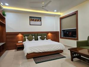 a bedroom with a large bed and a green couch at Hotel Sunrise in Damoh +7 photos