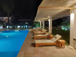 a row of lounge chairs next to a swimming pool at night at Amelia's Garden ΙΙ in Kavos