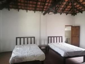 a bedroom with two beds and a table at Swastha Retreat in Polgahawila