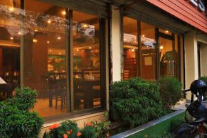 a restaurant with glass windows and a table at Hotel Peaceland Lumbini in Rummindei
