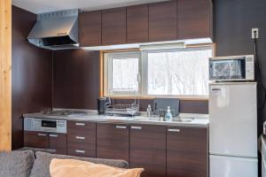 a kitchen with wooden cabinets and a white refrigerator at Goodfellas Onsen House in Niseko