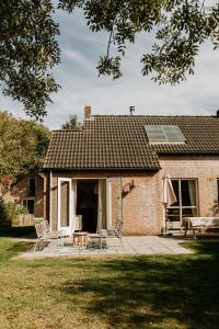 a brick house with two chairs and a patio at Bohemian Wellness met hottub & sauna in Ewijk