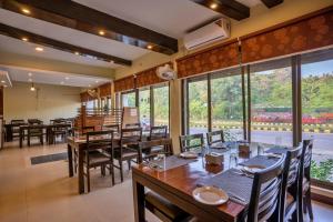 a restaurant with wooden tables and chairs and large windows at Hotel Peaceland Lumbini in Rummindei