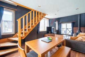 a living room with a wooden table and a staircase at Goodfellas Onsen House in Niseko