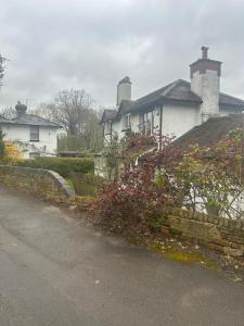 a white house with a stone wall next to a street at Stylish Home With Full Amenities in Yiewsley