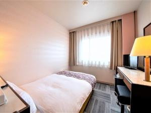 a hotel room with a bed and a desk and a window at Hotel Anesis Seto-Ohashi in Utazu