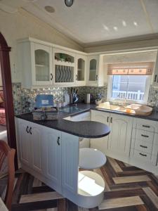 a kitchen with white cabinets and a black counter top at Caravan 6 berth in Ingoldmells