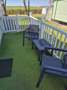 a porch with two chairs and a table and a fence at Caravan 6 berth in Ingoldmells
