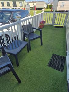 two blue chairs sitting on a lawn next to a fence at Caravan 6 berth in Ingoldmells +5 photos