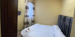 a bedroom with a bed with white sheets on it at E&V APARTMENT Berger Express in Iseri-Oke +4 photos