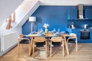 a dining room with blue walls and a wooden table and chairs at Le P'tit Bretzel in Turckheim