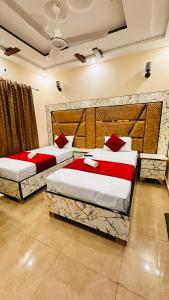 two beds with red pillows in a room at New Like Home Hotel in Lahore