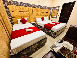 two beds in a hotel room with red sheets at New Like Home Hotel in Lahore