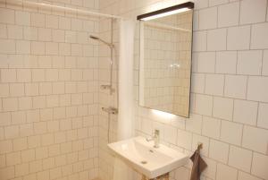 a white tiled bathroom with a sink and a mirror at Drängagården in Klagstorp