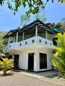 a large white building with a black door at Mirissa Villa Green Pepper in Mirissa