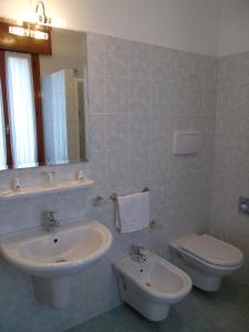 a bathroom with a sink and a toilet and a mirror at Hotel Alla Dolina in Sistiana