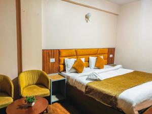 a hotel room with a bed and two chairs at Rare Himalayas Mansarovar in Darjeeling