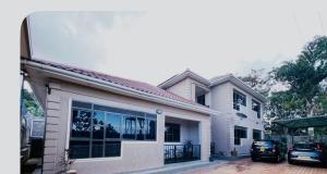 a white house with two cars parked in front of it at Gamaleo Apartment Namulanda in Namulanda