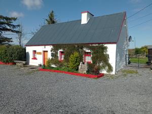 a small white house with a black roof at Historic old Cottage Co Mayo in Ballinrobe