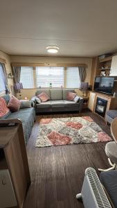 a living room with a couch and a rug at Buckley's Retreat - 3 Bedroom Family Caravan overlooking fishing lakes at Golden Palm Resort in Chapel Saint Leonards