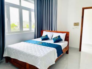 a bedroom with a bed with blue pillows and a window at Anh Duy Hotel in Nhơn Trạch