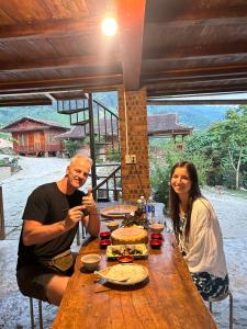 a man and woman sitting at a wooden table with food at ANOR - Farmstay - Double bed in Ha Tia