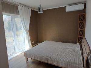 a bedroom with a bed and a large window at Brīvdienu māja in Jelgava