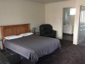 a hotel room with a bed and a chair at Charlton Motel in Gore