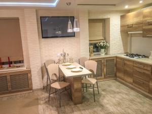 a kitchen with a table with chairs and a tv on the wall at Studio Luxe on Victory Street in the city center in Vinnytsya