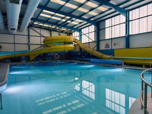 a swimming pool with a slide in a building at Buckley's Retreat - 3 Bedroom Family Caravan overlooking fishing lakes at Golden Palm Resort in Chapel Saint Leonards