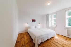 a white bedroom with a white bed and wooden floors at Kapitänshaus Wieck in Wieck