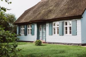 a cottage with a thatched roof on a lawn at Kapitänshaus Wieck in Wieck