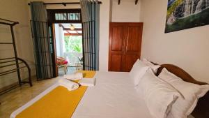 a bedroom with a bed with white sheets and pillows at Villa Mango Serenity in Hikkaduwa