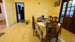 a dining room table with a white table cloth and wooden chairs at Villa Mango Serenity in Hikkaduwa